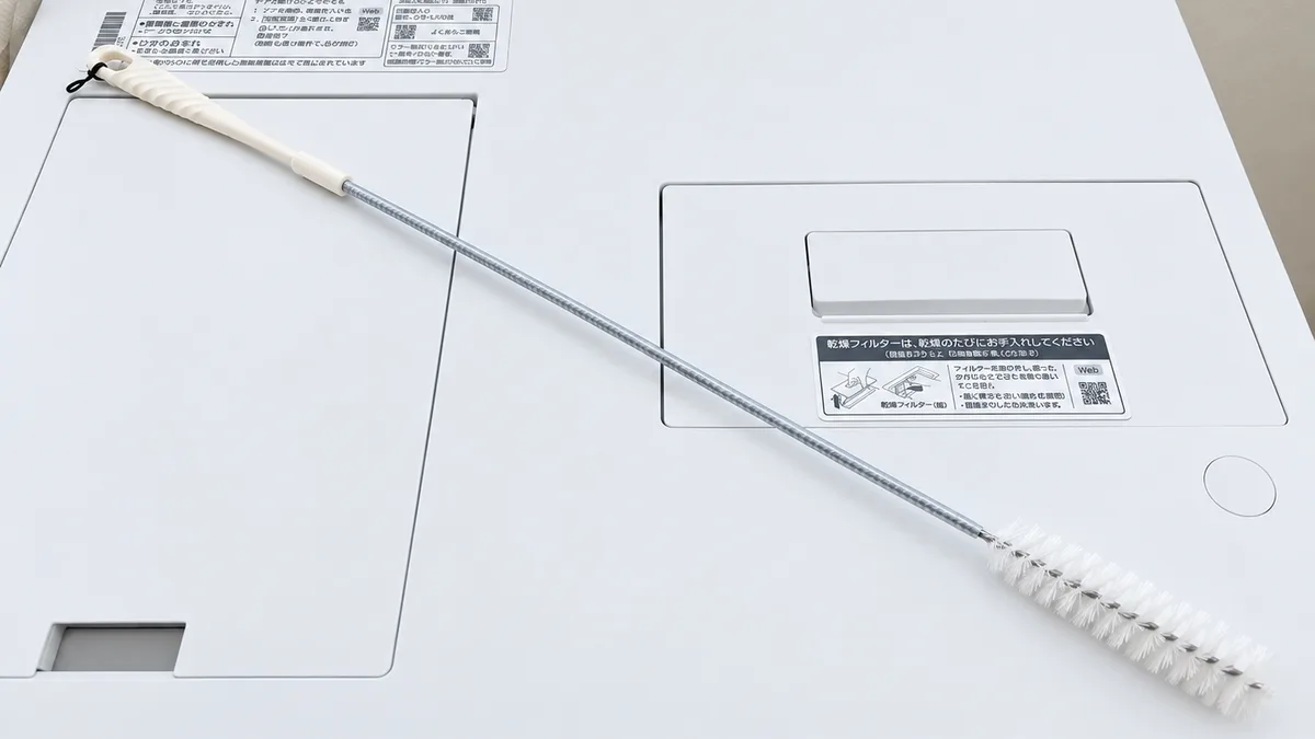 NA-LX127Eの購入特典のおそうじブラシを洗濯機の上に置いた様子