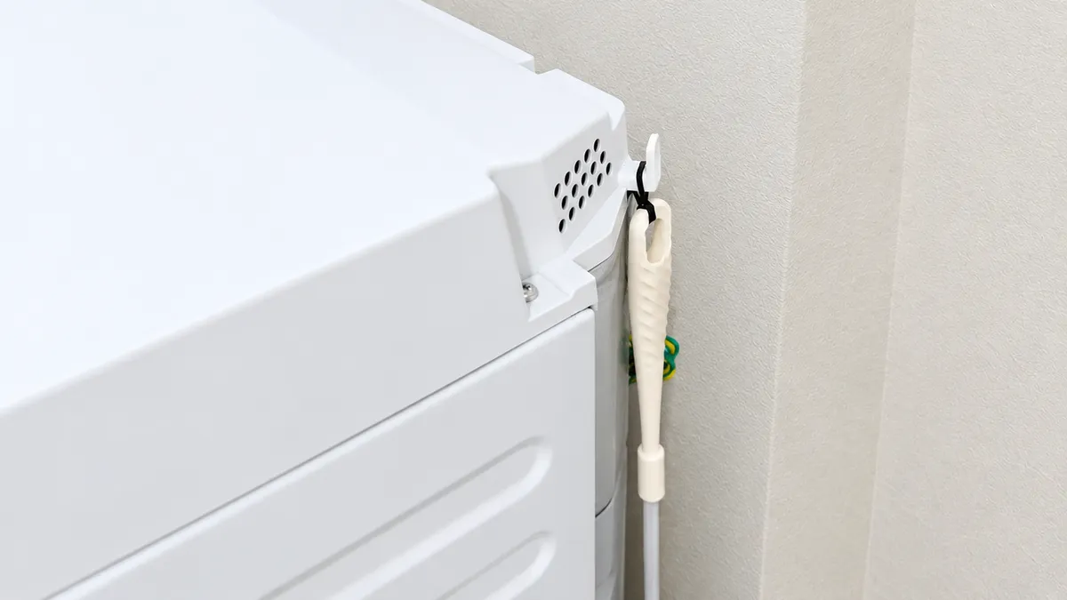 おそうじブラシを洗濯機の側面に掛けて収納している様子